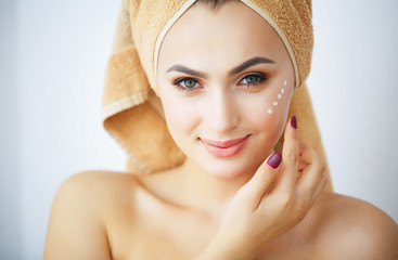 Beauty and Care. Portrait of a Girl with a Brown Towel on the Head. Young Woman With Pure Skin. Holds Cream in Hands. to Apply Cream for face. High Resolution