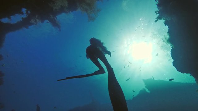 Freediver ascending to water surface from wreck in deep ocean