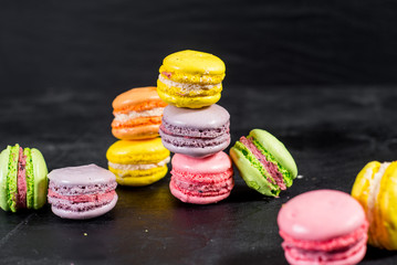 Many colored macaroons on black background