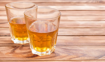 Two glasses of whisky on wooden background. Space for text.