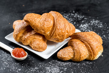 Tasty croissants with jam filling on black background