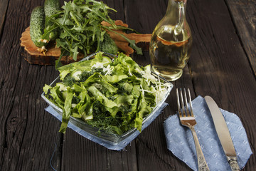 Vegetable salad with fresh vegetables and arugula on a wooden table. Salad with green fresh vegetables in a glass bowl. Vegetarian food salad. The concept of a healthy diet