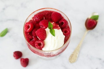 Strawberry Sunday with raspberries, decorated with mint leaves and served in a classic old glass goblet.