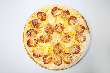 round pizza with pieces of sausage, cheese and seasonings is on a wooden board in the center of the table