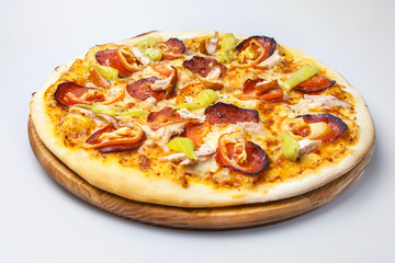 juicy cheese pizza with bits of bacon, with meat of chicken and with pepper is on a round board on a white background