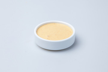a plate of sauce with sour cream stands on a table on a white background