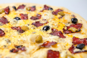 aromatic pizza with bacon, seasonings, cheese and vegetables is on the table in the pizzeria