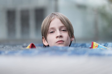 Portrait of a boy floating in a lifejacket in the pool