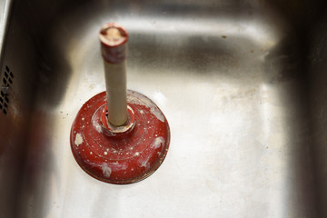 Fototapeta na wymiar A plunger used to clean a clogged / blocked kitchen sink
