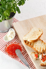toasts with butter and Red caviar on a wooden cutting Board