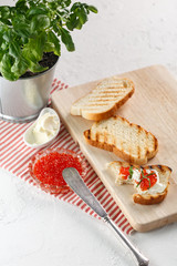 toasts with butter and Red caviar on a wooden cutting Board