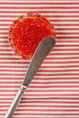 Red caviar in a Cup on a textile background. Decorated with a knife. Top view