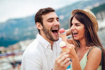 Happy couple having date and eating ice cream on vacation. Sea background.