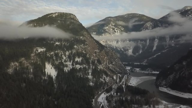 Aerial 4k footage of a river passing in the valley between the mountains in the Canadian Winter Landscape. Taken near Hope, British Columbia, Canada.