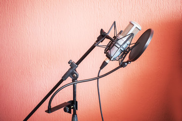 Fototapeta na wymiar Microphone on a stand with an orange wall in the background