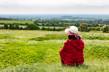 Woman enjoy view of farm lands while sitting down in field