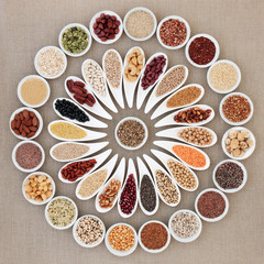 Vegan high protein dried health food collection with nuts, seeds, legumes, pasta, grains and cereals. Foods high in fibre, antioxidants, anthocyanins, vitamins and minerals. Top view on hessian.