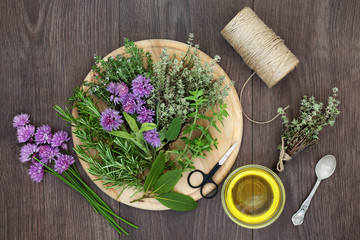 Herb preparation with fresh herbs, oil, string, oil and scissors on rustic oak background. Top view. 