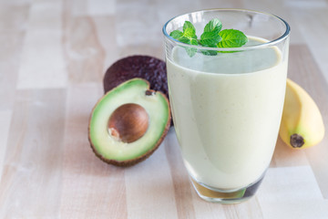 Healthy smoothie with avocado, banana, milk and honey on wooden background, horizontal, copy space