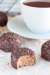 Swedish sweets Arrack balls, made from cookie crumbs, cocoa, butter and coconut wine Arrack flavour, on wooden table with cup of tea, vertical