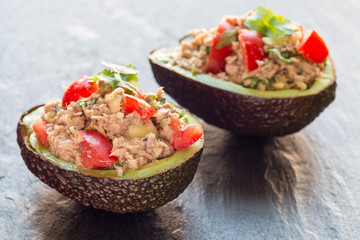 Salad with tuna, avocado, tomatos, coriander and lemon juice served in avocado bowl, horizontal