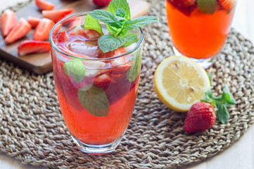 Homemade iced tea with strawberries and mint on a wooden table, horizontal