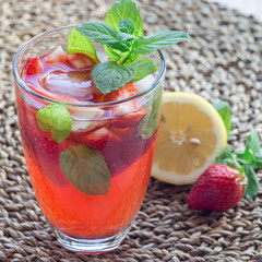 Homemade iced tea with strawberries and mint on wooden table, square
