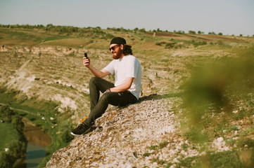 Obraz premium Happy bearded man using phone outside. Travel concept