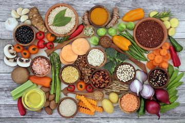 Health food for fitness concept with fruit, vegetables, pulses, herbs, spices, nuts, cereals, grains, olive oil and himalayan salt. High in antioxidants, fibre, smart carbs, minerals and vitamins.