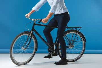 Fototapeta premium cropped shot of stylish man sitting on bicycle on blue