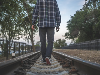 back of  lonely man walking far away on the railway track