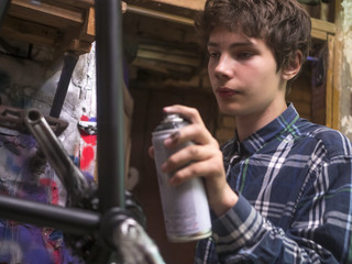 Fototapeta na wymiar close up young man painting the bmx bicycle with spray can in the workshop