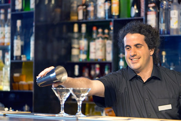 Professional barman man pours a fresh cocktail to the customers of the hotel bar. Focus on the bartender. The concept of service. Focus on the bartender.