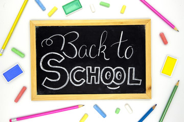 Back to school white chalk lettering on blackboard with colorful art supplies. Back to school banner template.