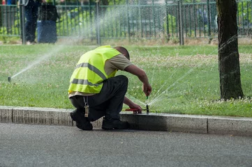 Gordijnen Olijfgroen transportation company employee adjusting automatic sprinklers on tramway line  © pixarno