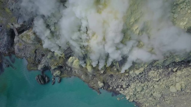 Aerial shot of mine workers extracting sulfur in extreme working conditions at Kawah Ijen volcanic crater lake Indonesia