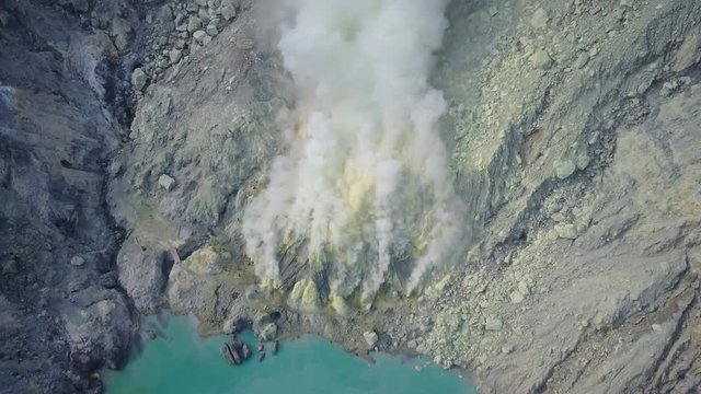 Overhead drone shot of dangerous sulfur gas billowing from mining site near Kawah Ijen volcanic crater lake in Indonesia
