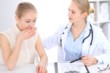 Blonde female doctor and patient talking in hospital office. Health care and client service in medicine