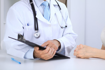 Doctor and patient talking while sitting at the table . Concept of support and trust in medicine