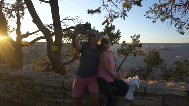 A mature couple taking a selfie at the Grand Canyon at sunset
