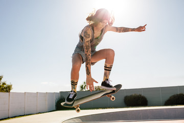 Women skater doing ollie on skateboard - obrazy, fototapety, plakaty
