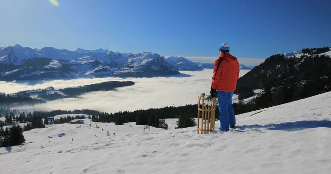 Young attractive man ready to go sledding in Alps during winter holiday, Ibergeregg, Switzerland