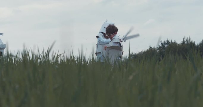 Brothers boys wearing handmade medieval knight armor costumes having a sword fight near cardboard castle. 4K UHD 60 FPS SLO MO