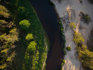 Naklejka na ściany i meble top view to bending river in green forest on sunse