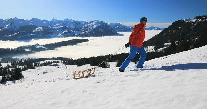 Young attractive man ready to go sledding in Alps during winter holiday, Ibergeregg, Switzerland