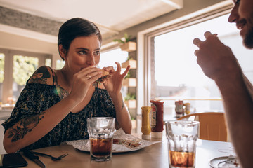 Woman having burger with boyfriend at restaurant