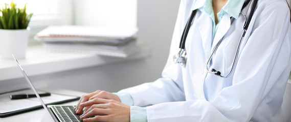 Close up of  unknown female doctor sitting  at the table near the window in hospital
