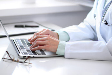 Close up of  unknown female doctor sitting  at the table near the window in hospital