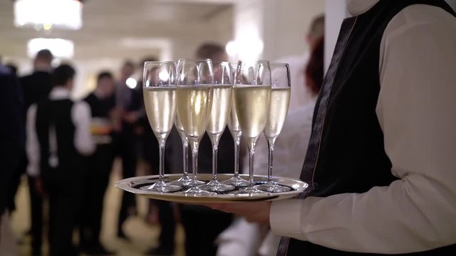 Waiter holding plate with glasses of champagne at the party