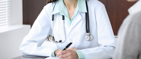 Doctor and  patient  sitting at the desk near the window in hospital